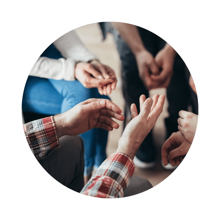 Individuals sitting in a circle, hands clasped together, representing solidarity and collaboration.