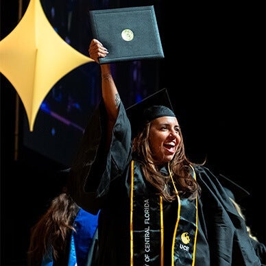 UCF graduate showing off their degree at commencement