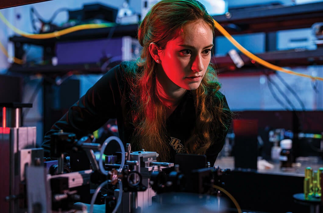 A female student works with laser technology in an optics and photonics laboratory at UCF.