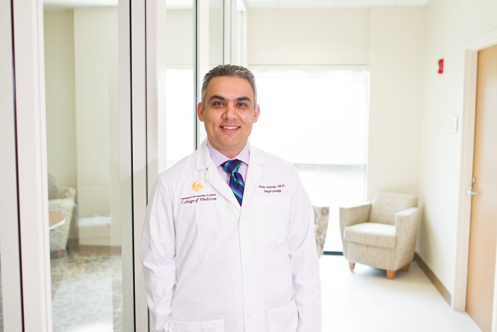 Male doctor wearing a white lab coat stands in a hallway