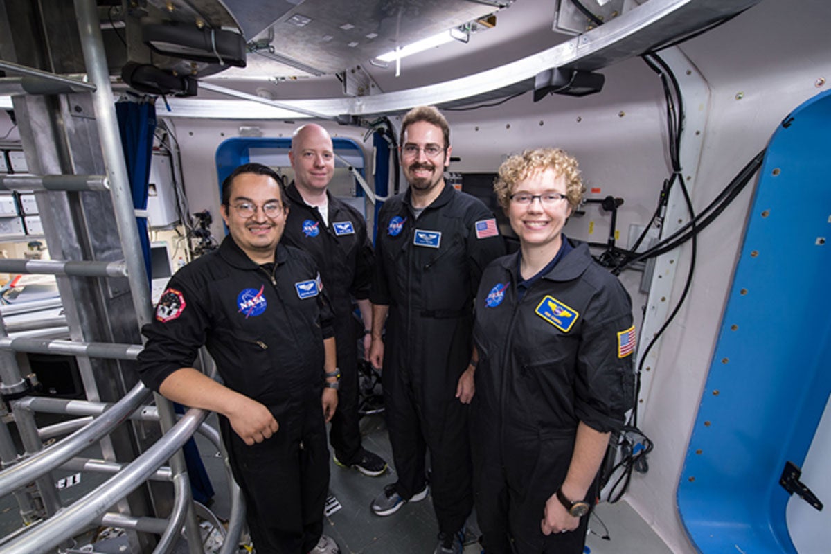 Four people standing in a space shuttle