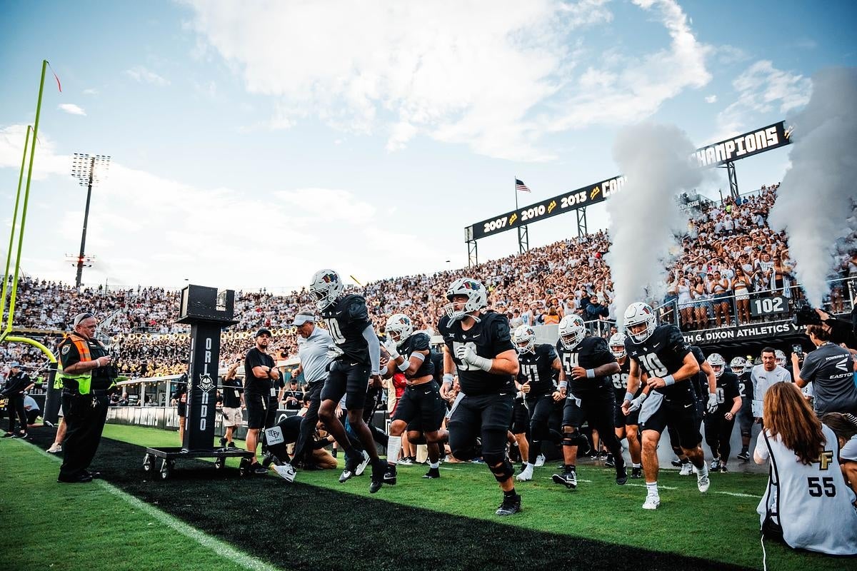 UCF football players run onto the field before a game