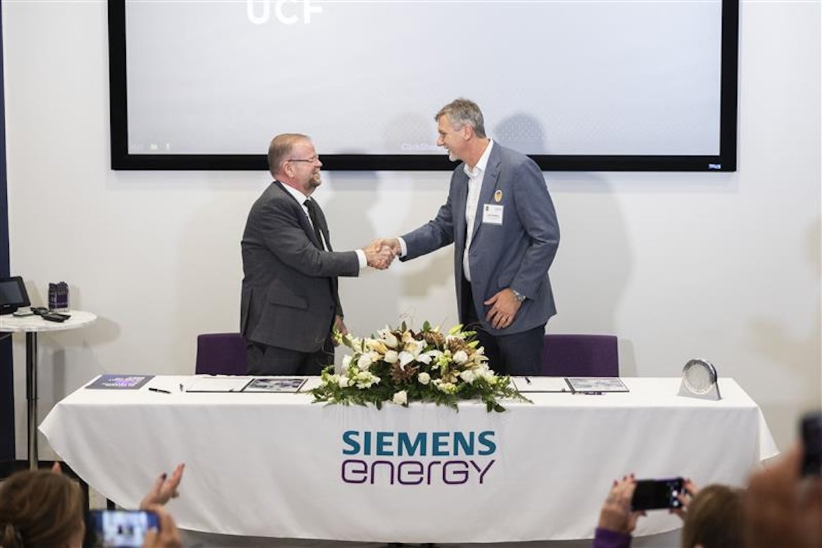 Two men shaking hands behind a table that says Siemens Energy