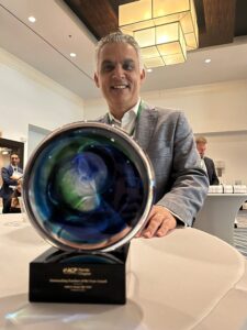 Male doctor poses with an award that's sitting on a table