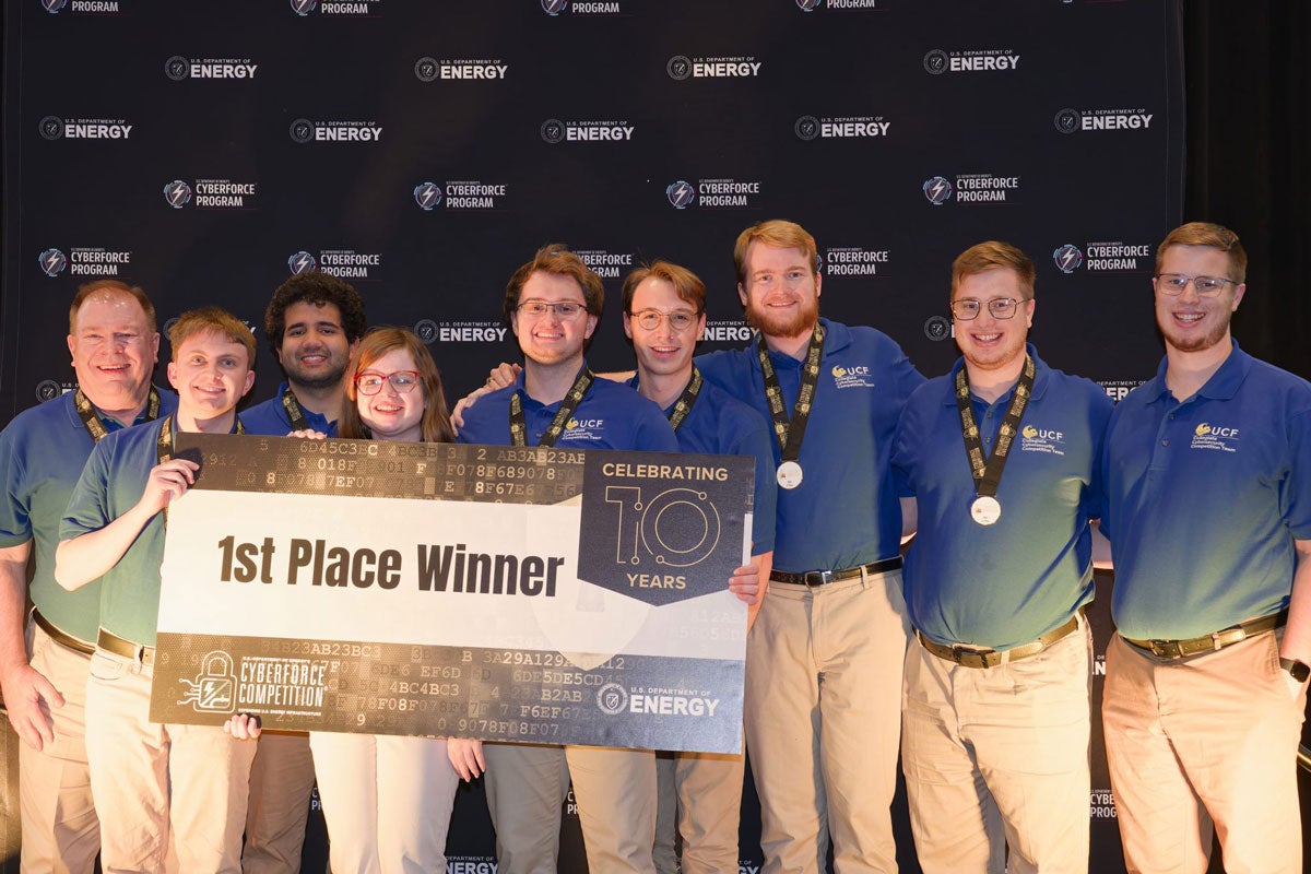 A team of UCF cyber students holding a 1st place winner sign