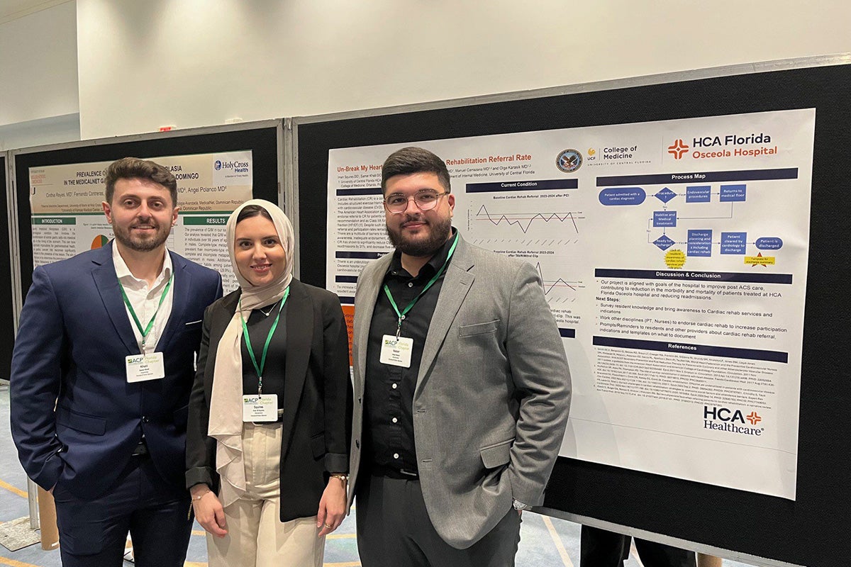 Three students stand in front of their medical research poster 