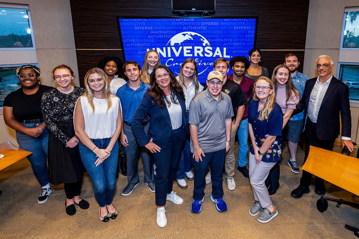 UCF students pose with Universal Creative Team Members for a group photo in a conference room