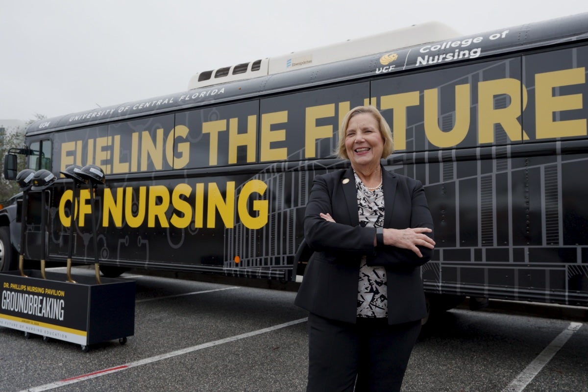 A woman standing in front of a bus that says "Fueling the future of nursing"