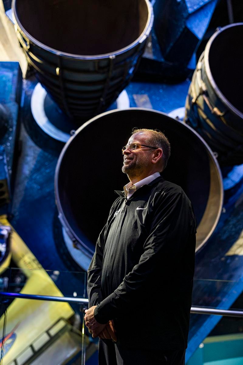 UCF President Alexander N. Cartwright stands next to rocket engines in a facility at NASA's Kennedy Space Center