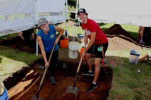 Two students digging dirt with shovels