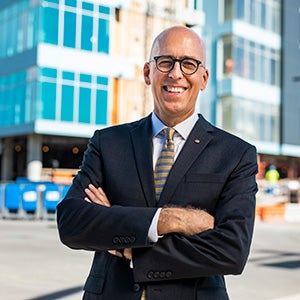 Headshot photo of a man wearing a suit standing on a street in downtown Orlando