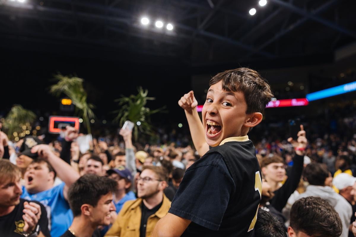 UCF fans celebrate the Knights on the basketball court at Addition Financial Arena