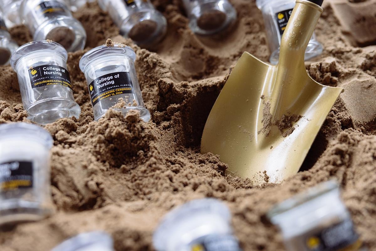 Glass jars filled with dirt surround a shovel 