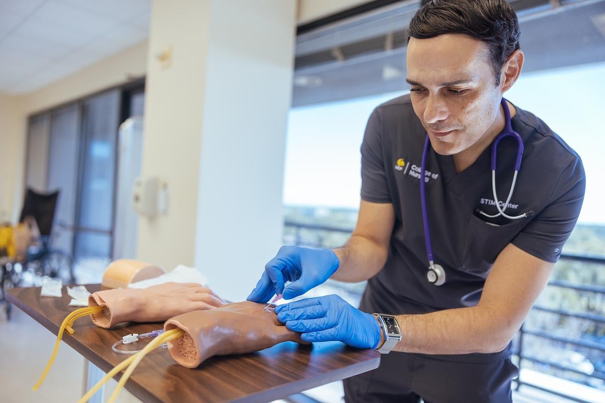 A UCF College of Nursing student working on a hand manikin in a lab