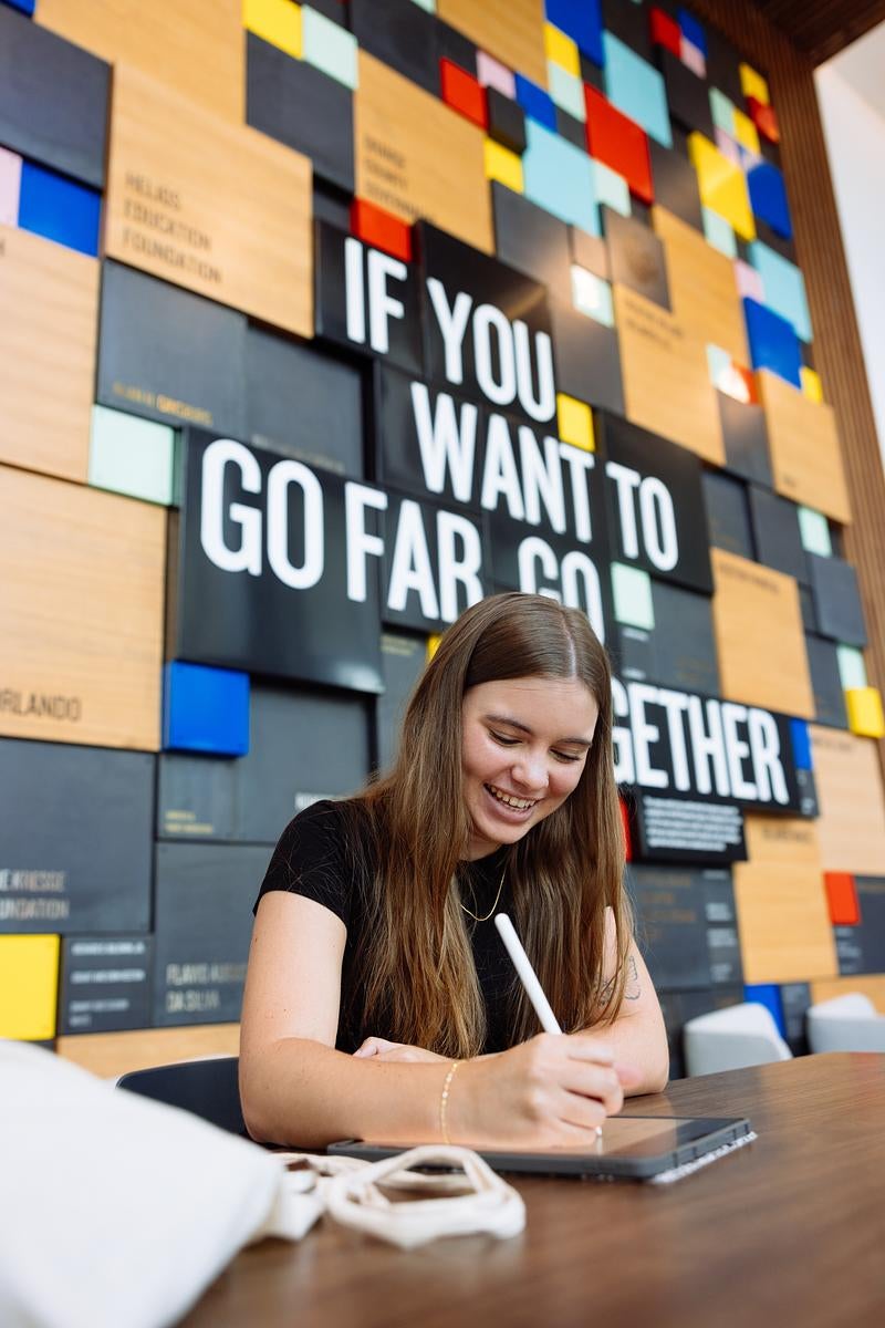 A student sits at a table working on her tablet at the UCF Downtown campus