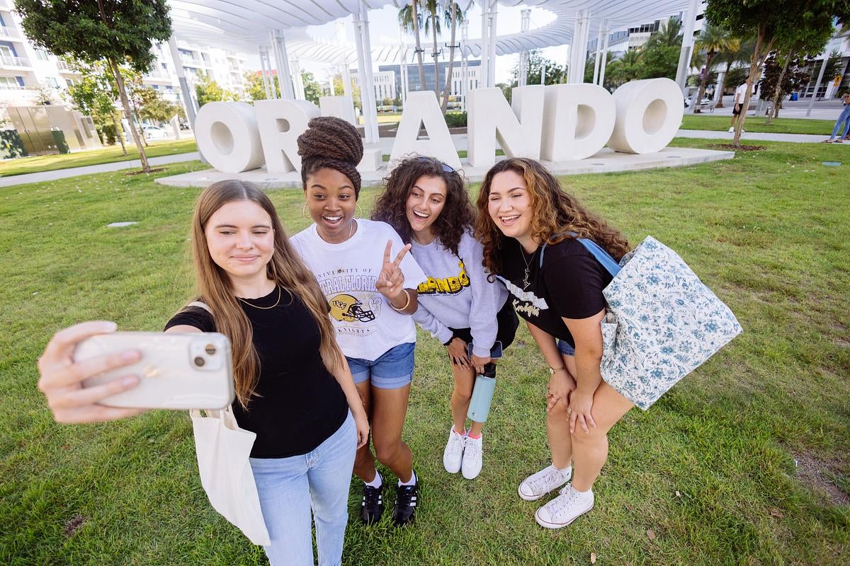 Four students take a selfie in front of the Orlando sign downtown