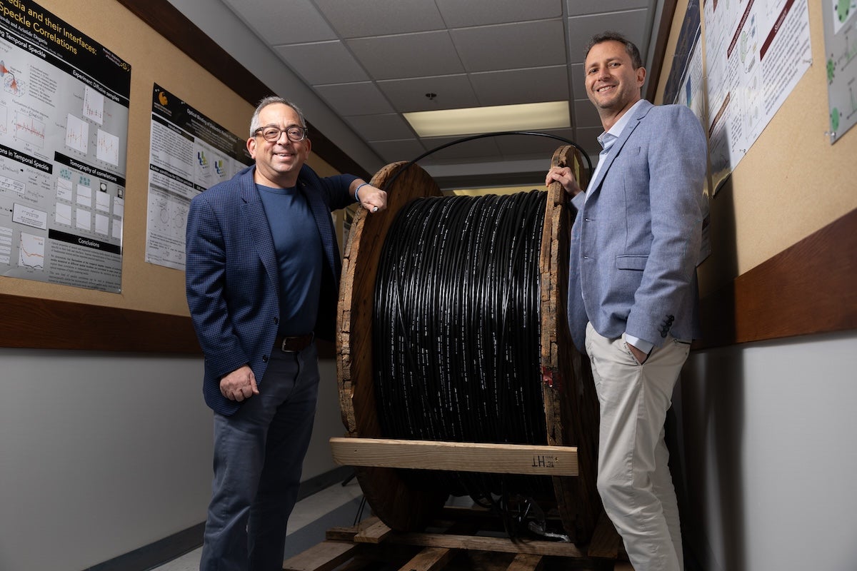 Jason Eichenholz and Rodrigo Amezcua Correa standing in front of a spool of hollow core fibers