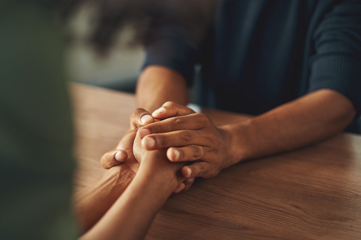 Close-up of a man holding a woman's hand over a wooden table