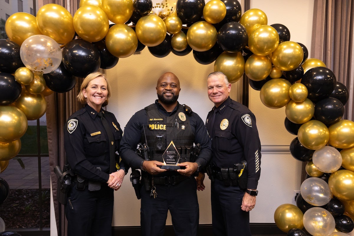 Surrounded by black and gold balloons, Sgt. Terrell Alexander poses for a photo with UCFPD Chief Carl Metzger and Deputy Chief Robin Griffin-Kitzerow