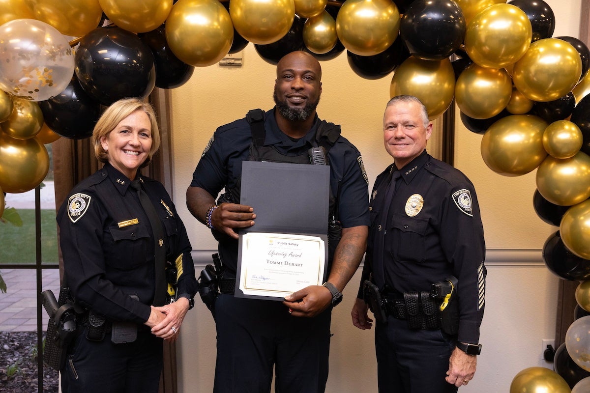 Surrounded by black and gold balloons, UCFPD Officer Tommy Duhart poses for a photo with Chief Carl Metzger and Deputy Chief Robin Griffin-Kitzerow