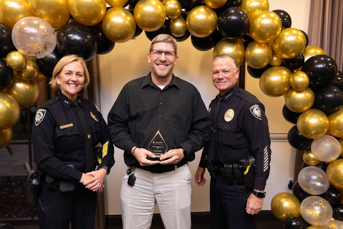 Surrounded by black and gold balloons, Steven Freund poses for a photo with UCFPD Chief Carl Metzger and Deputy Chief Robin Griffin-Kitzerow