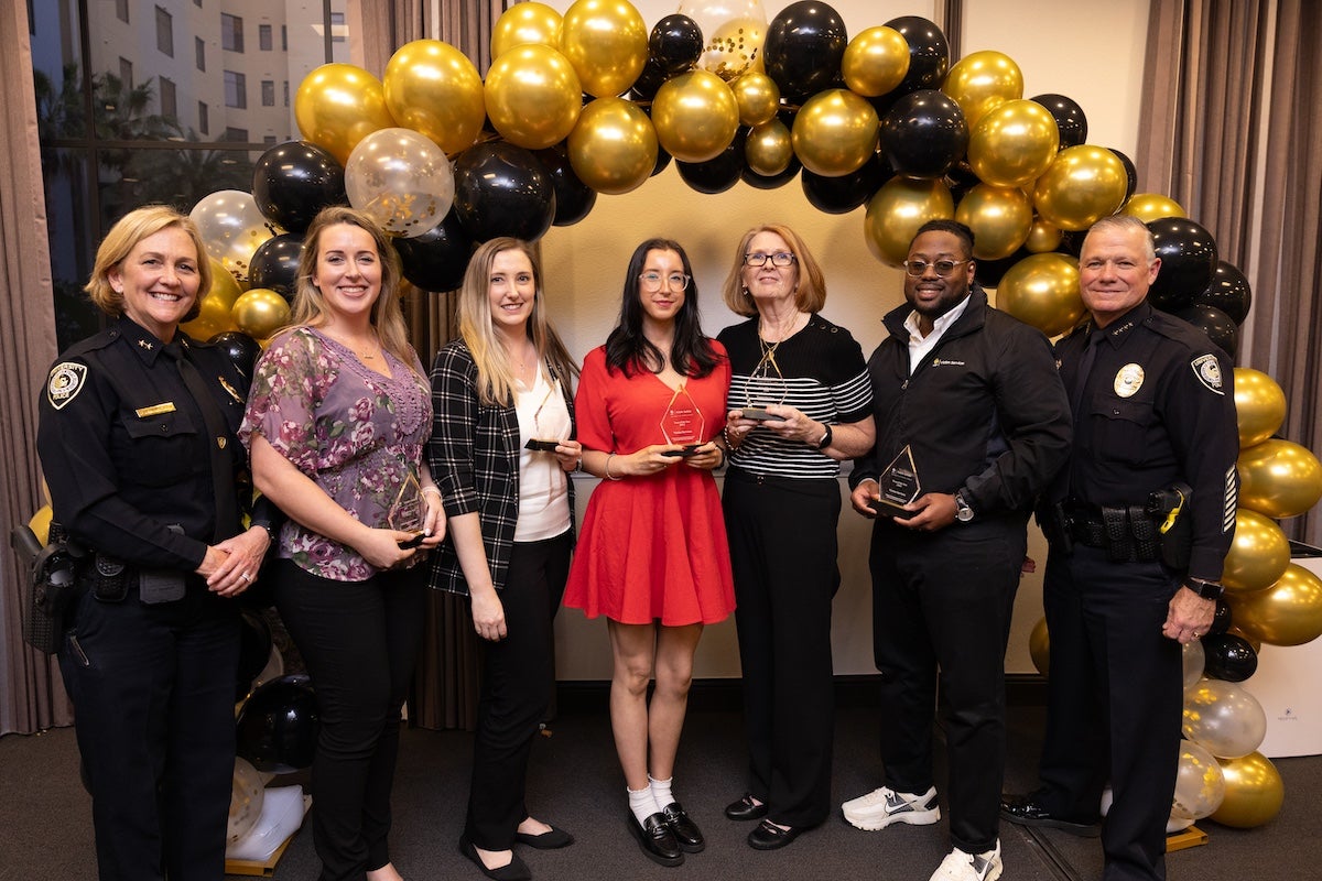 Surrounded by black and gold balloons, members of the UCF Victim Services team pose for a group photo with UCFPD Chief Carl Metzger and Deputy Chief Robin Griffin-Kitzerow