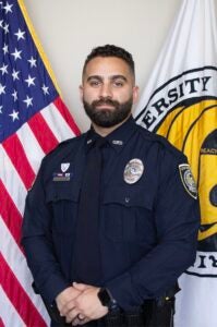 UCFPD Officer Andres Carbone stands in front of UCF and United States flags