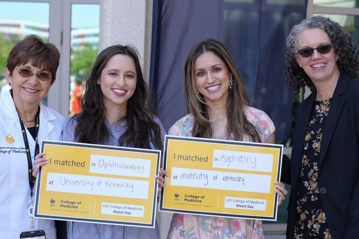 UCF College of Medicine Dean Deborah German with two students holding Match Day signs and another woman