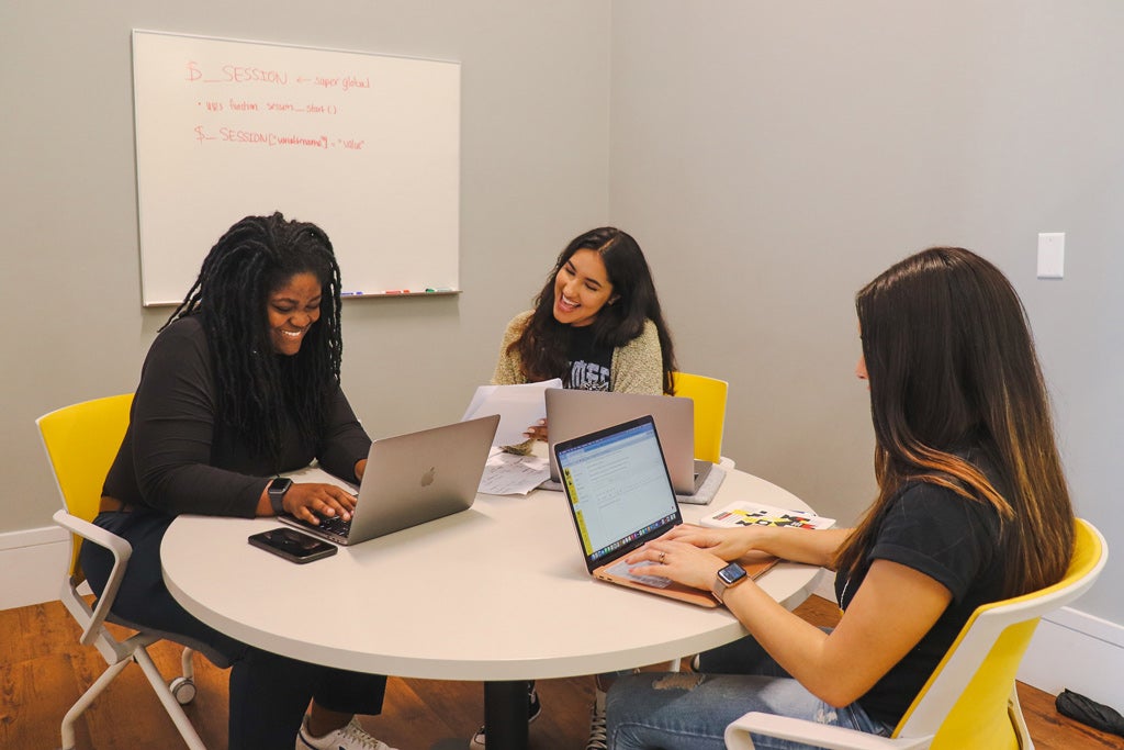 students together around a table with laptops