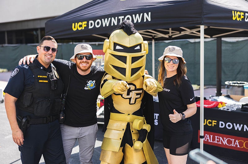 People posting for a photo with Knightro under a UCF Downtown tent