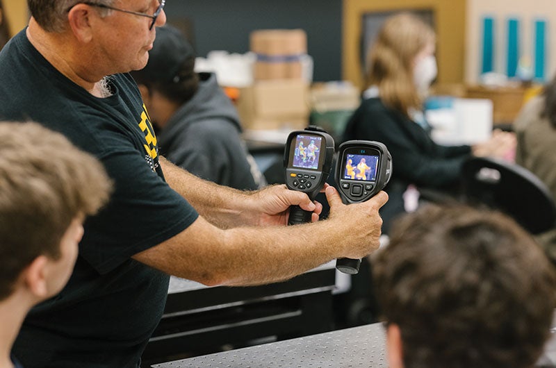 A faculty member holding tech devices