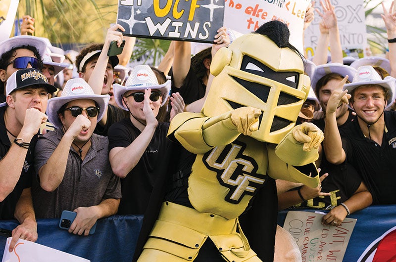 Knightro pointing with a crowd of people behind him