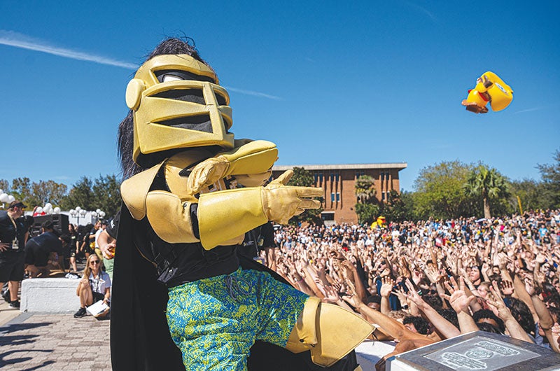 Knightro throwing a rubber duck to a crowd of people at Spirit Splash